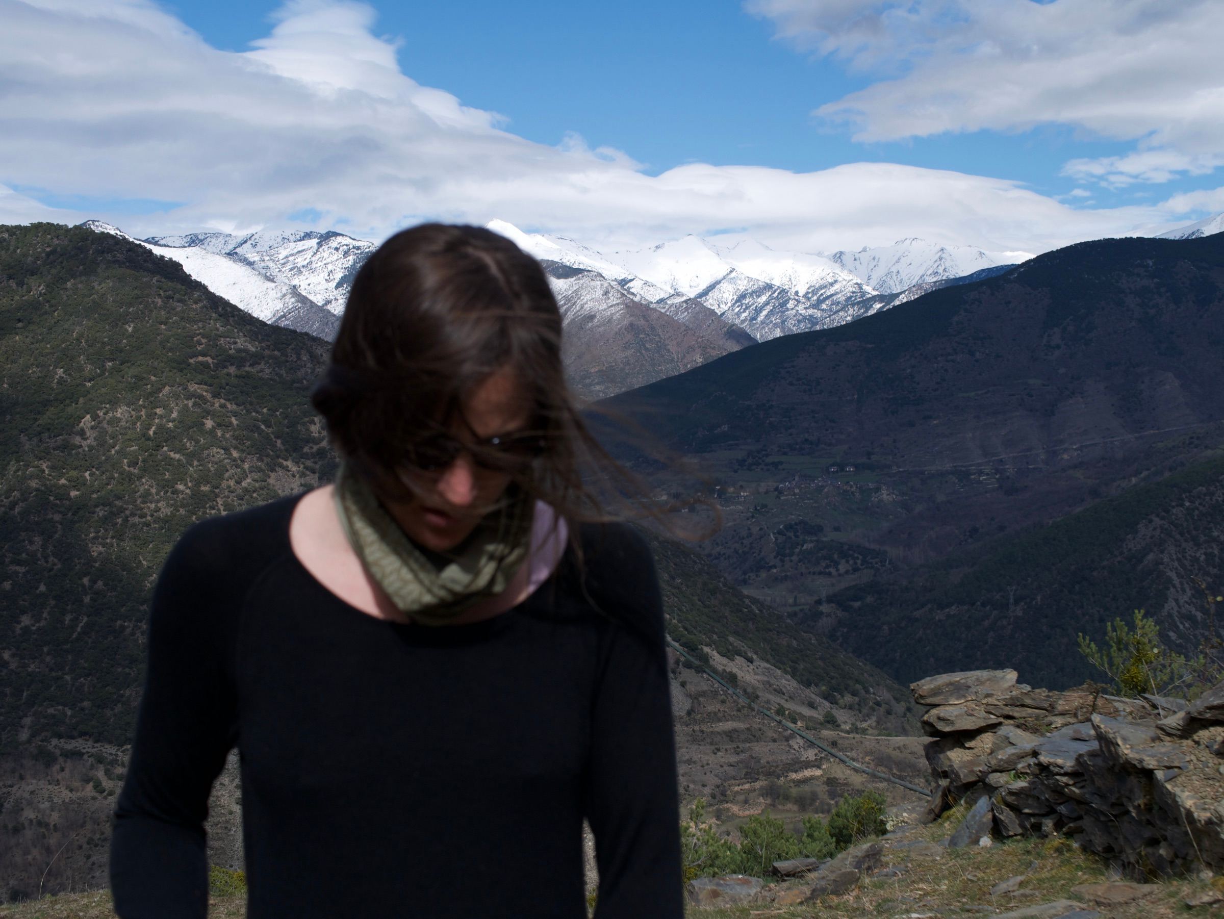 Mujer con el pelo al viento frente a montañas nevadas
